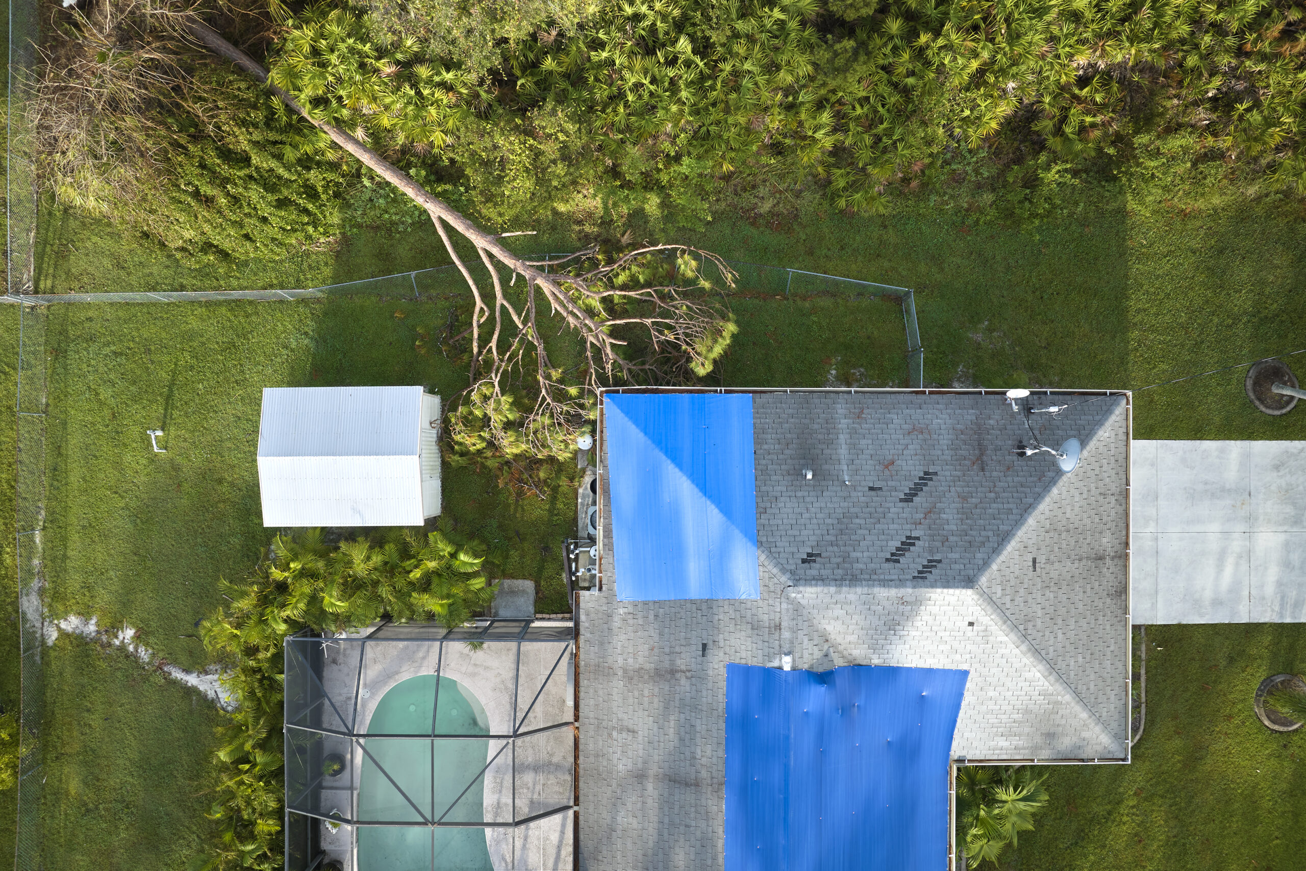 Top view of leaking house roof covered with protective tarp sheets against rainwater leaks.