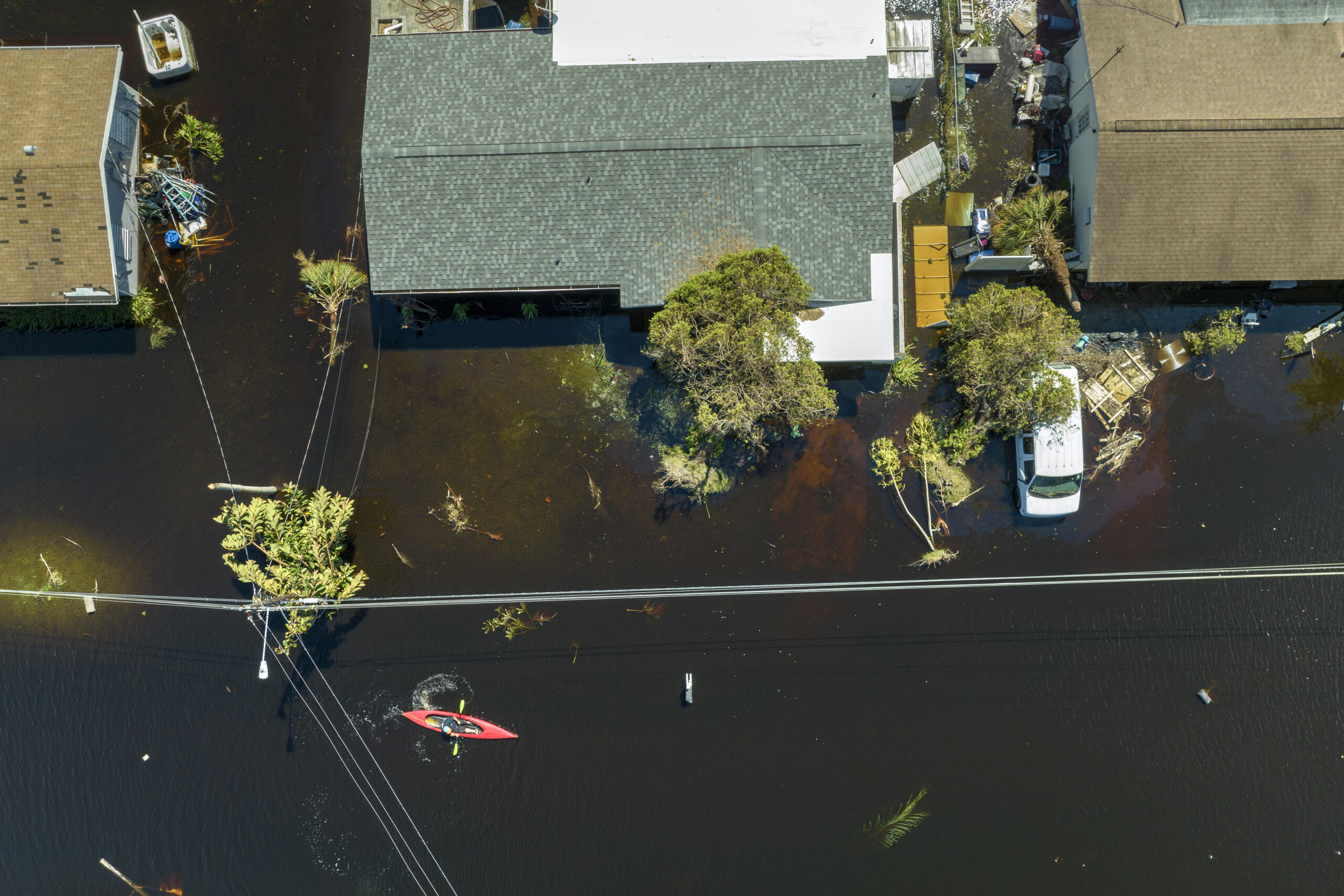 Kayak boat floating on a residential area's flooded street.
