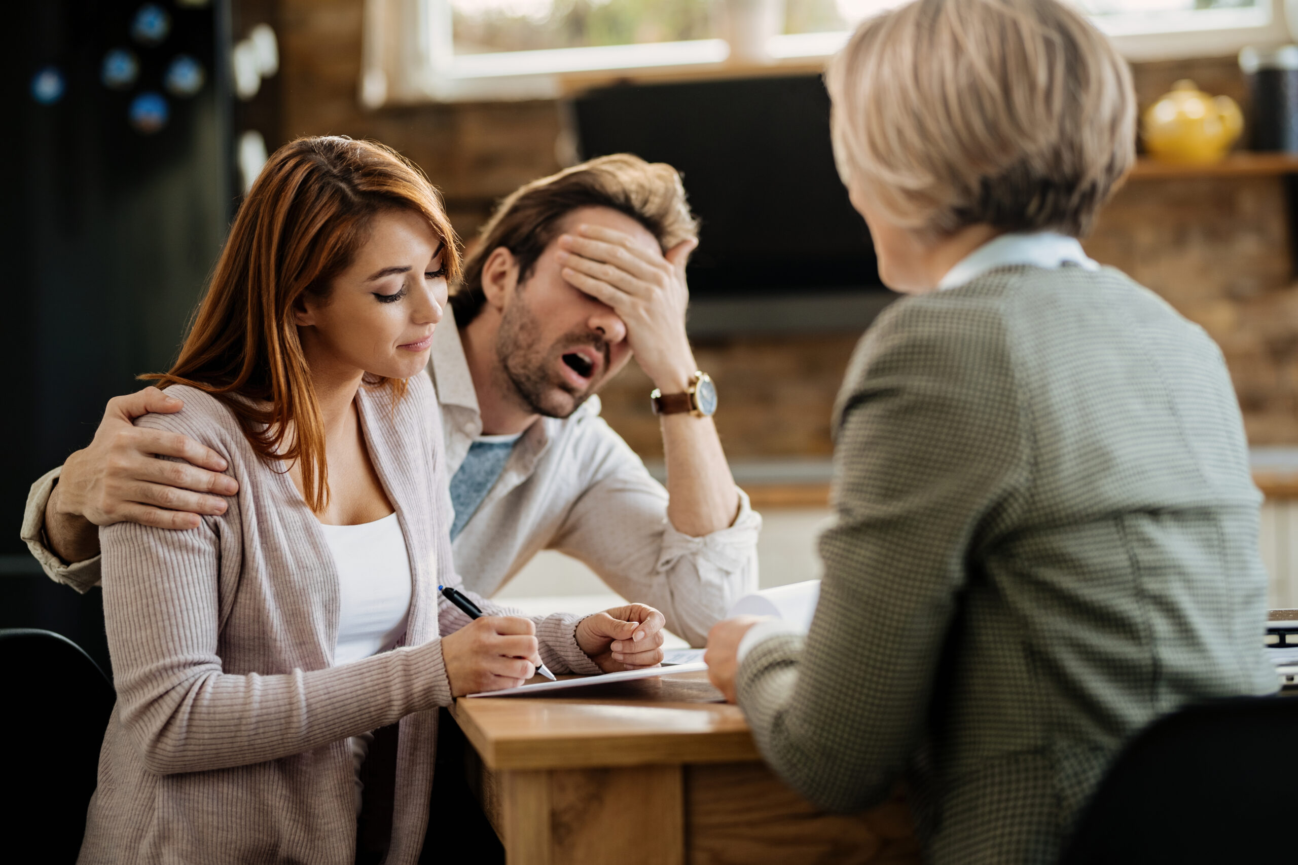 Couple look stressed while signing a paper.