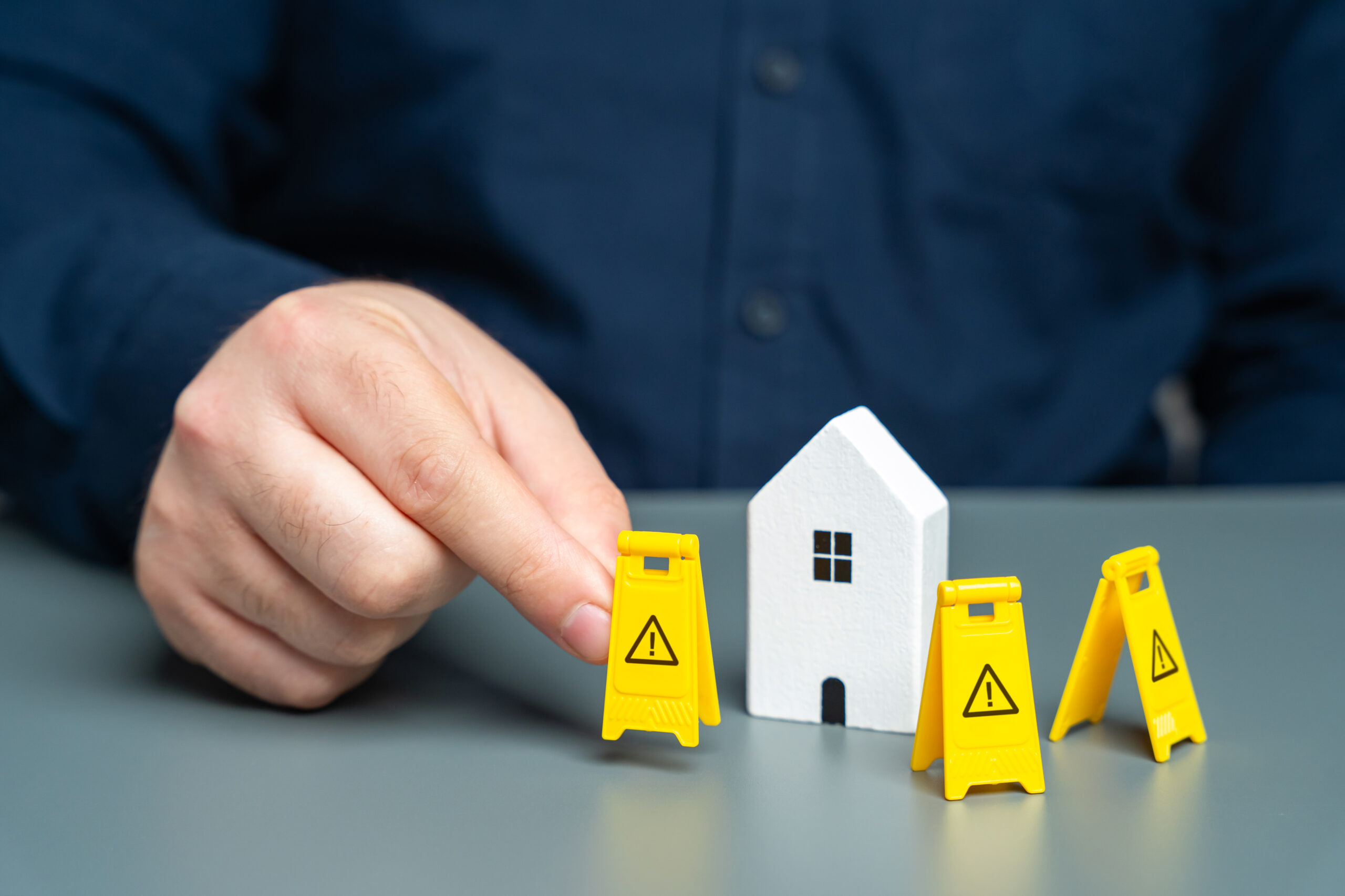 A man installs restriction signs around a model house.